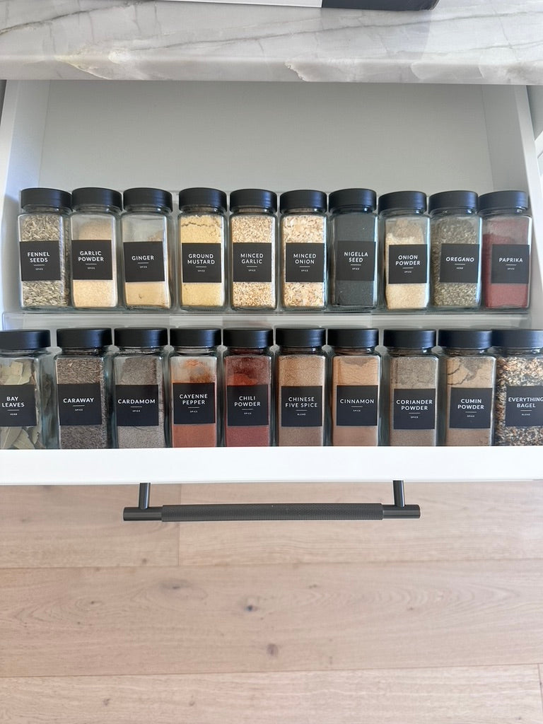 spice jars neatly organized on an acrylic spice drawer organizer