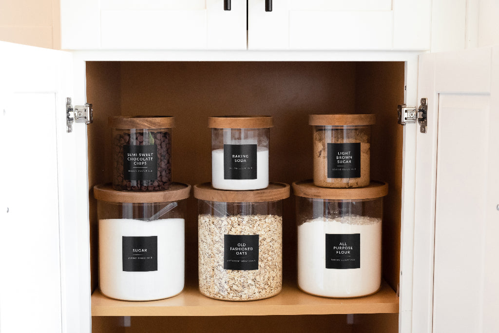 Open white kitchen cabinet with glass jars labeled with black minimalist pantry labels - Savvy & Sorted