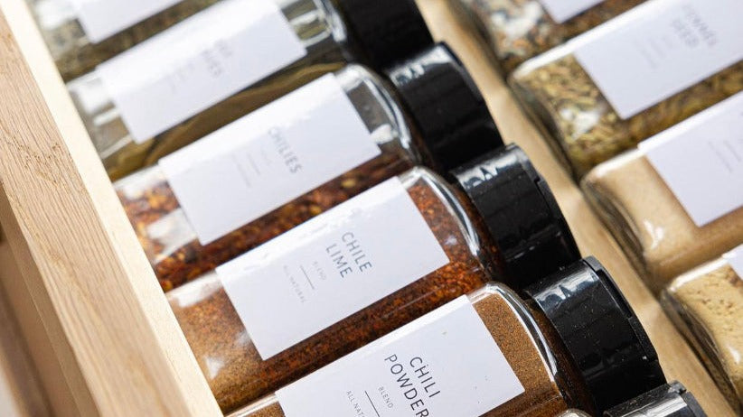 Organised spice drawer with uniform glass spice jars and bamboo lids featuring minimalist white labels — Savvy &amp; Sorted
