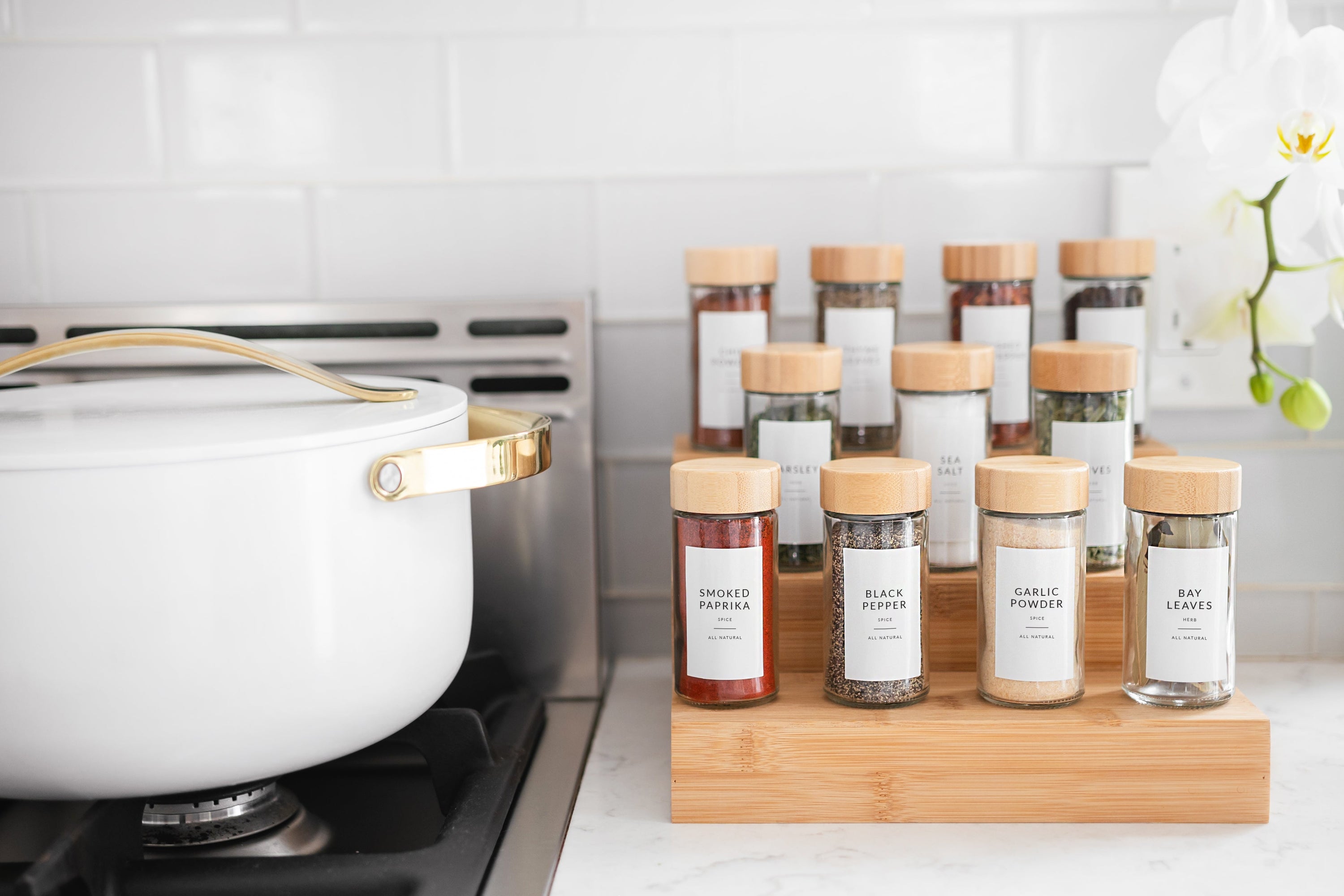 White Dutch oven with tiered bamboo spice rack and labeled glass spice containers in aspirational kitchen - Savvy & Sorted
