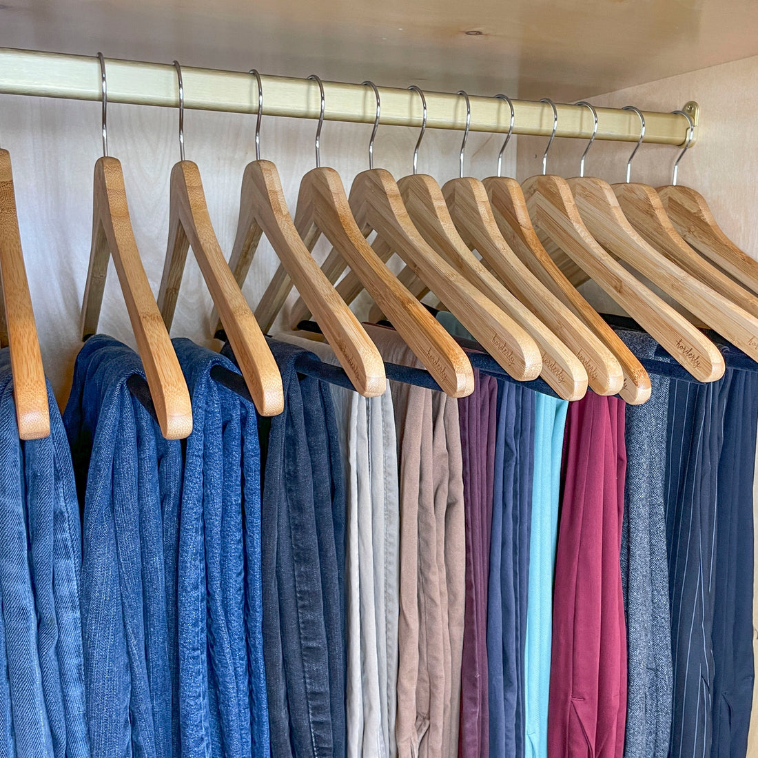Row of wooden hangers with colorful pants on a rack.