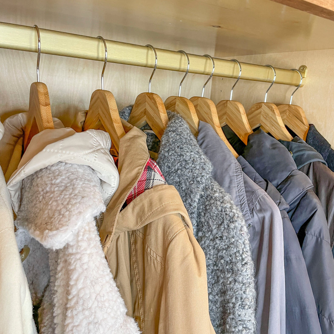 Clothing items on wooden hangers in a closet