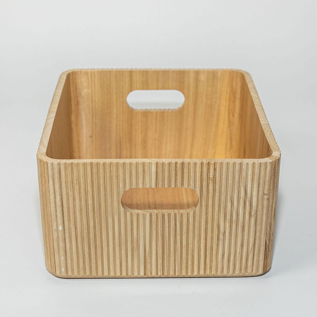 Wooden storage basket with handles on a light gray background