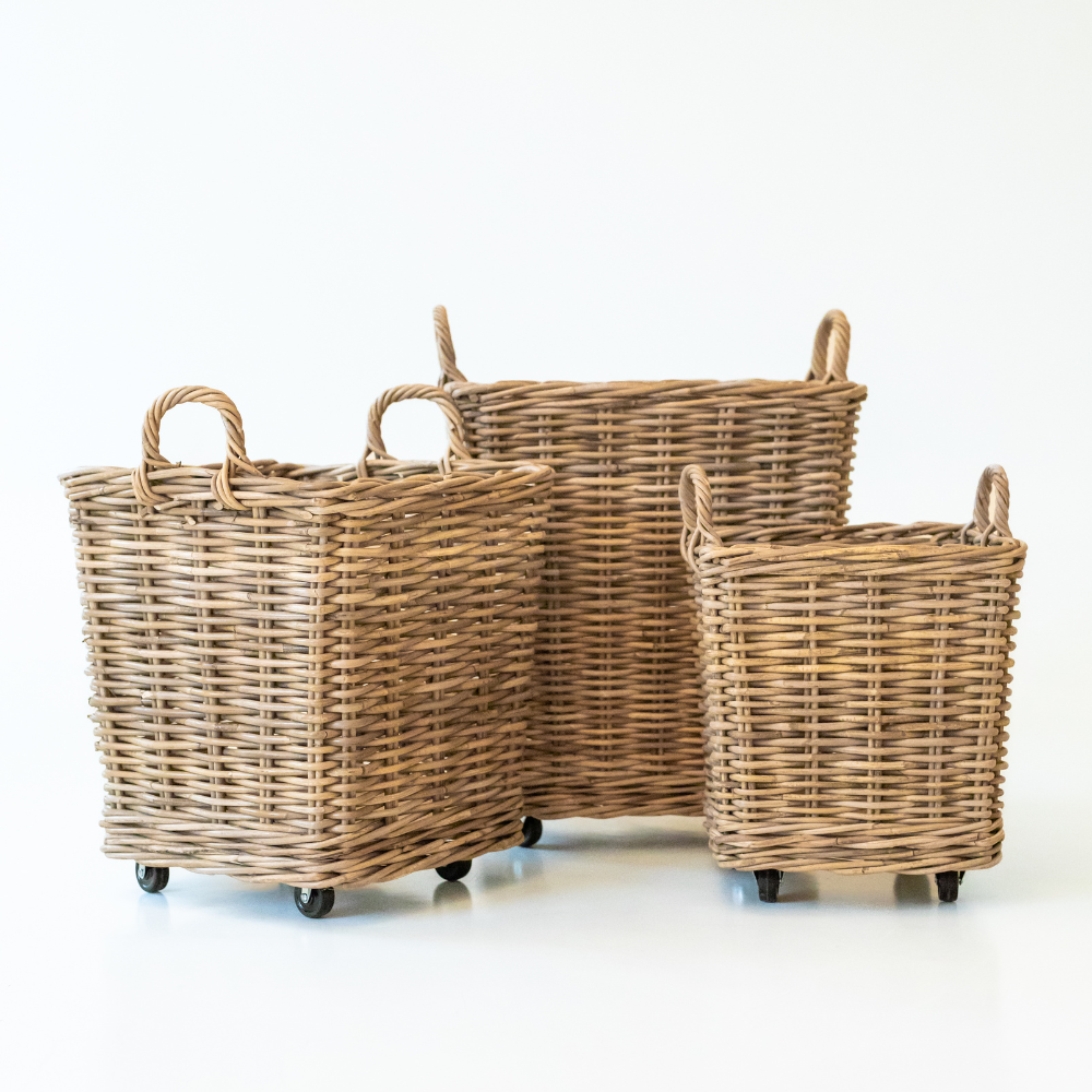 Three wicker baskets of different sizes on wheels against a white background