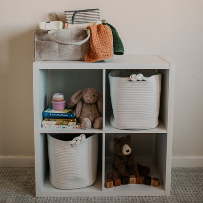 White storage cube with toys and baskets on a neutral background