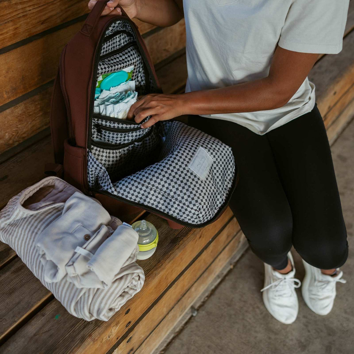 Person packing a bag with clothes on a wooden bench