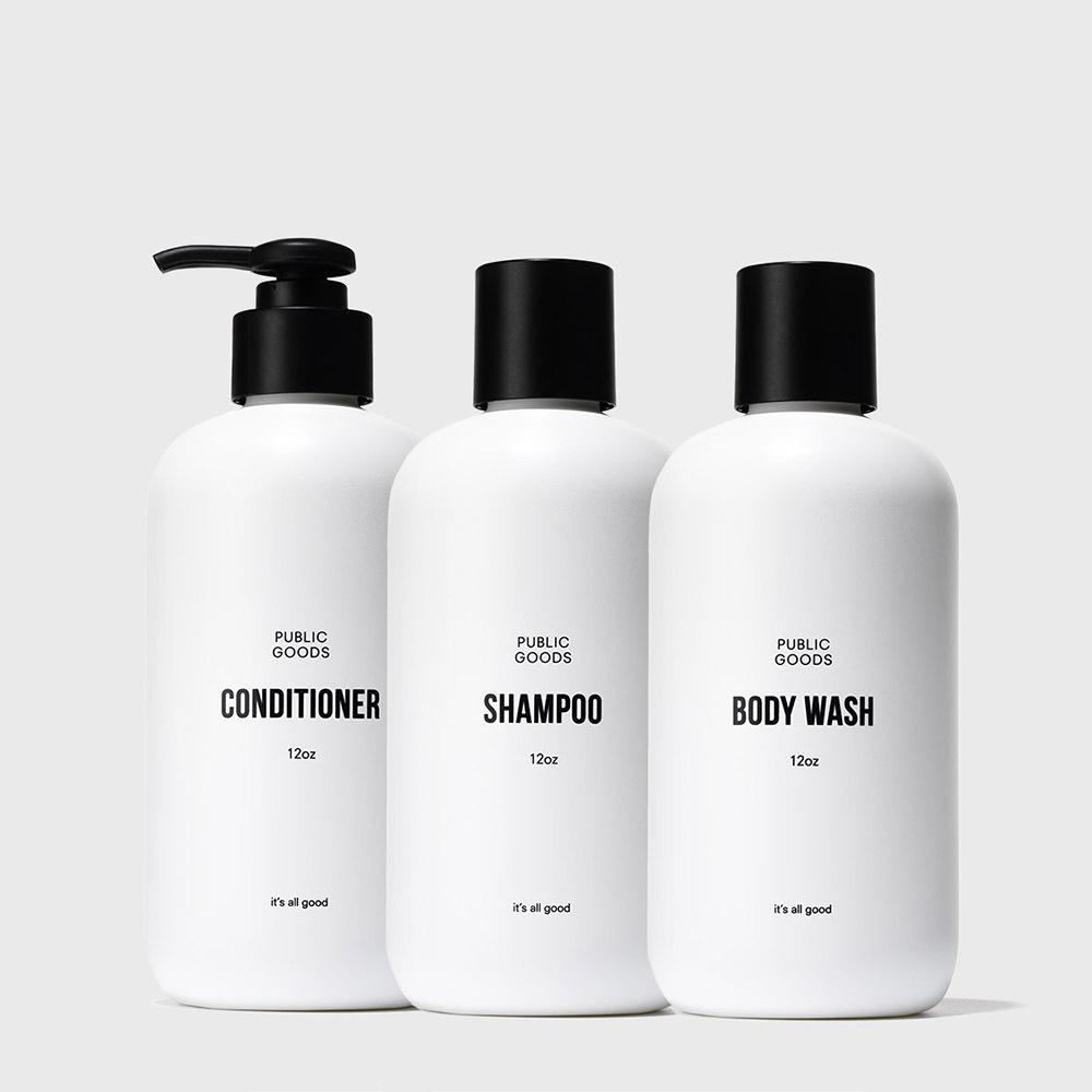 Three bottles of Public Goods shampoo, conditioner, and body wash on a white background