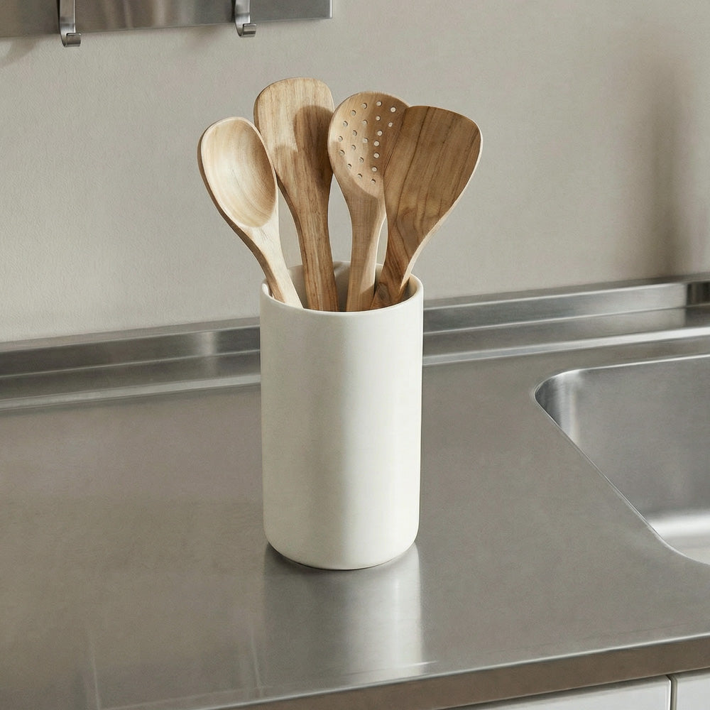 Set of wooden spoons in a white container on a kitchen counter.
